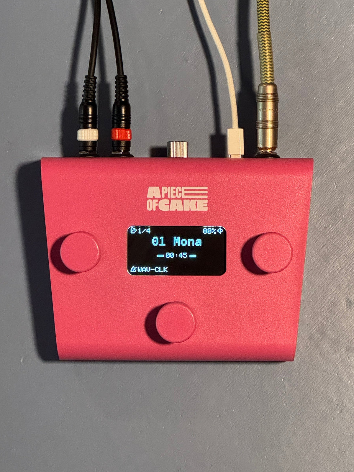 Pink A piece of cake backing track player from above, cables plugged in, screen showing a song with a WAV click track loaded
