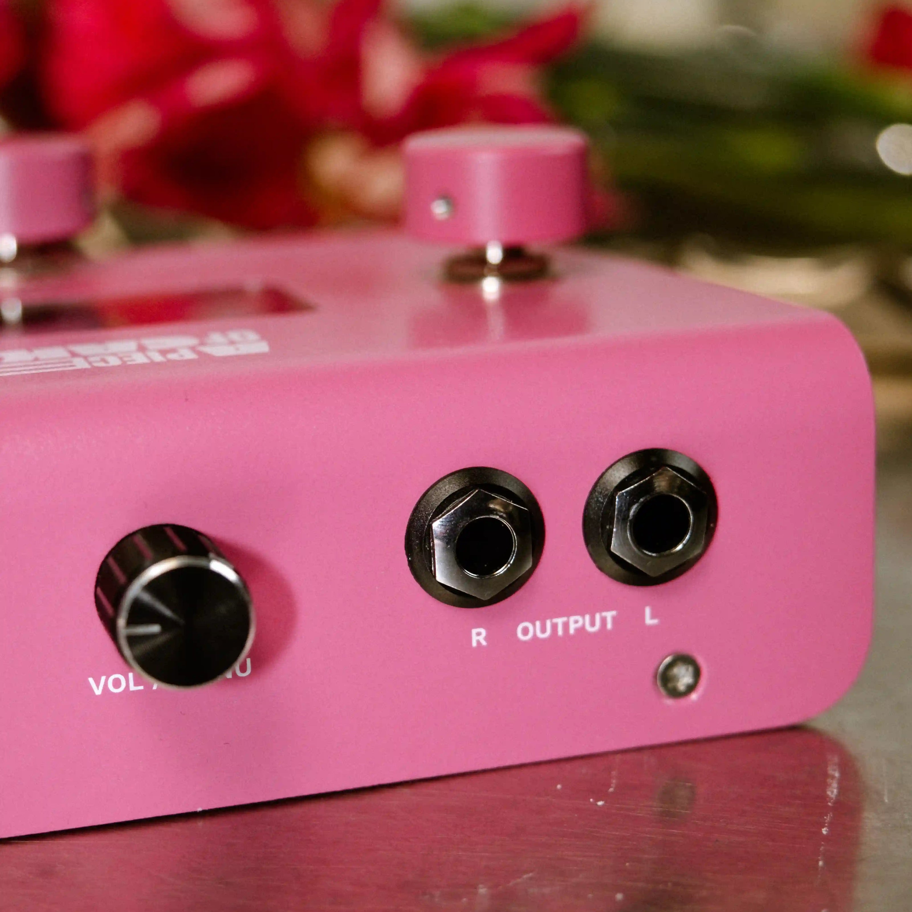 Close-up of a pink electronic A piece of cake device with control knobs and labels on a reflective surface.