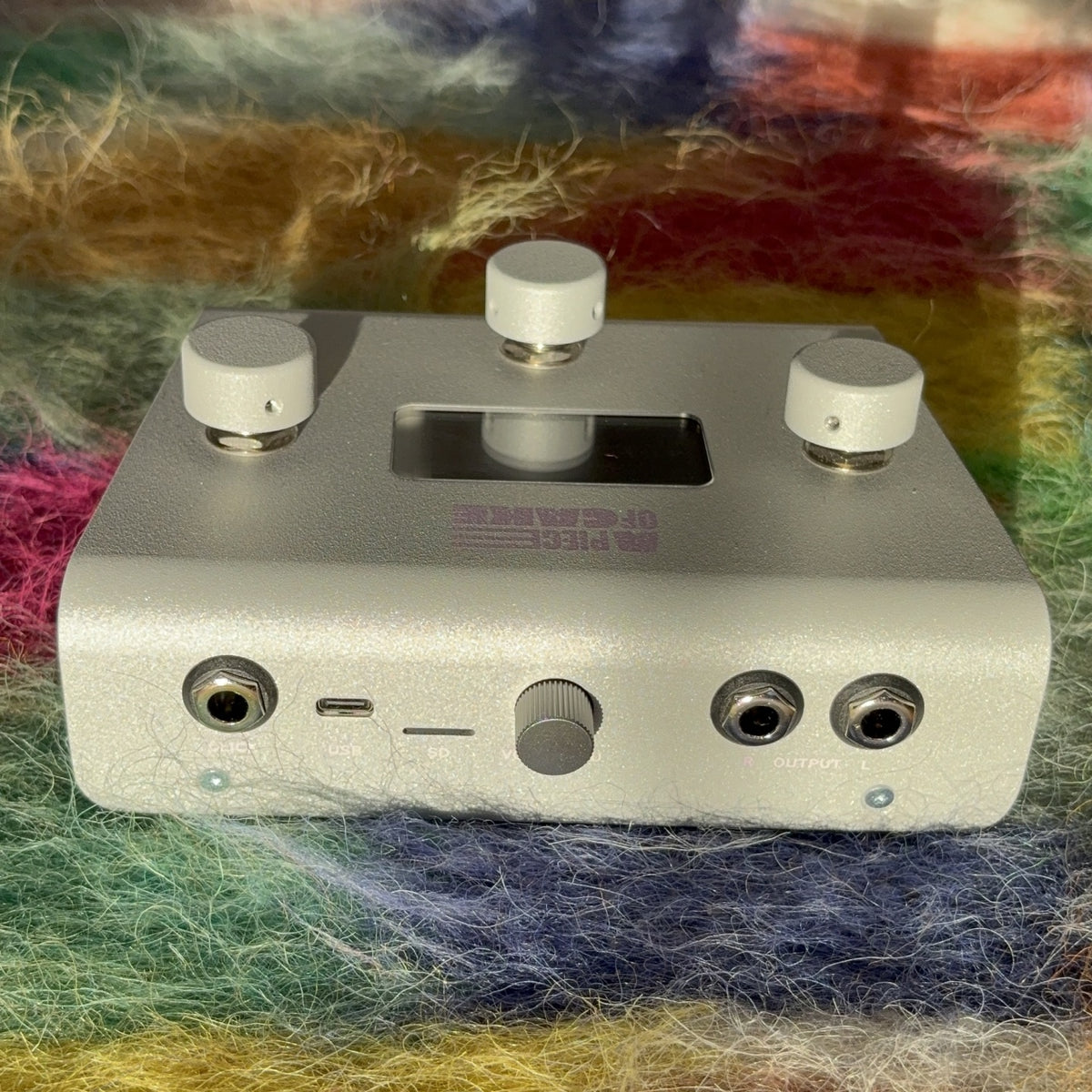 Back panel of the silver A piece of cake pedal showing click out, USB-C, SD card slot and stereo outputs